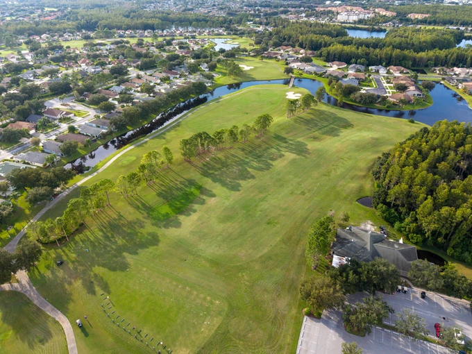 Aerial view of homes around an open green landscape and a lake