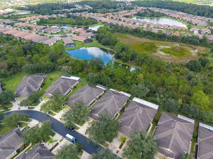 Homes beside woodland and a small lake under soft daylight