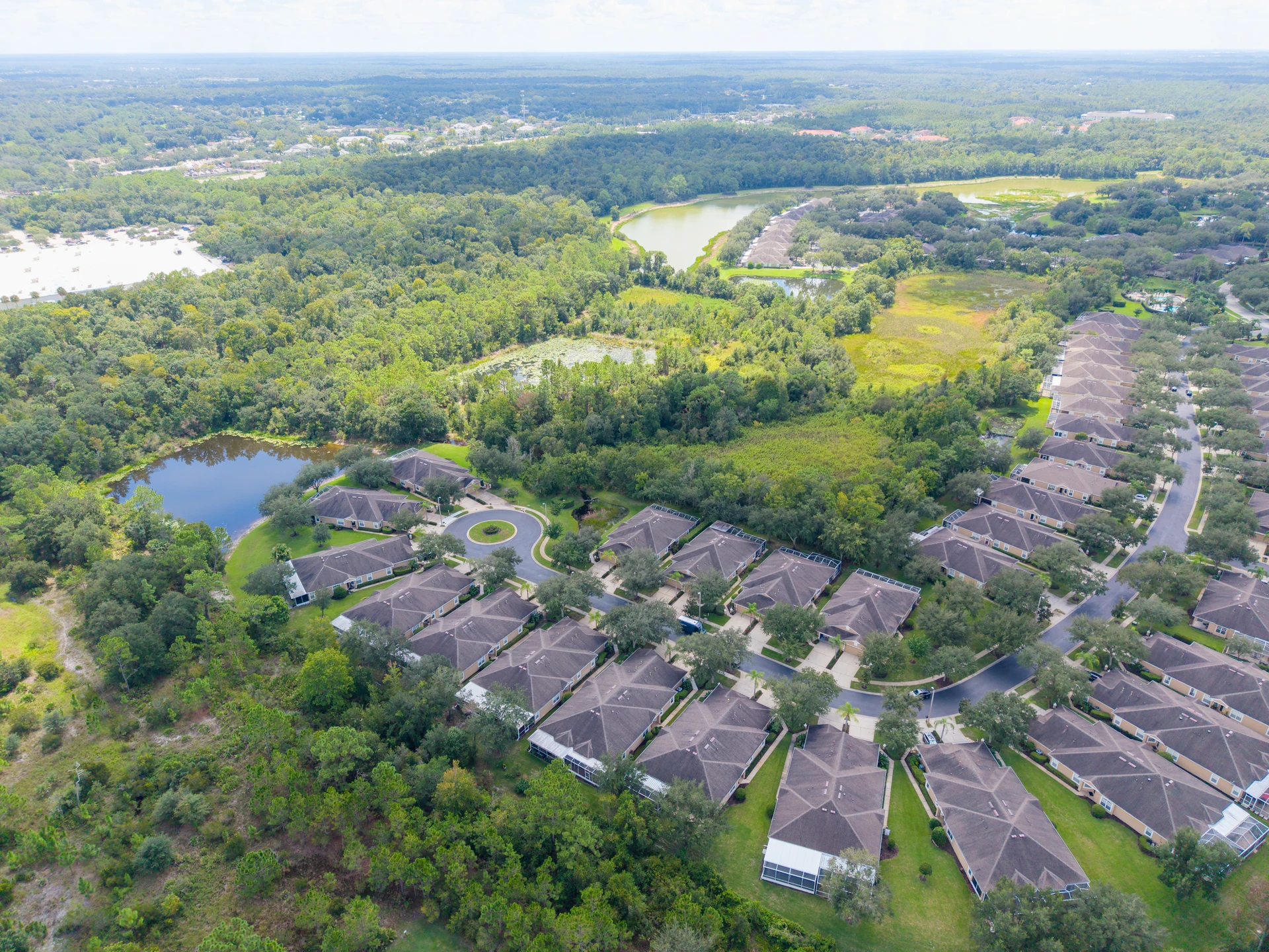 Attached homes beside wooded areas and lakes, viewed from above
