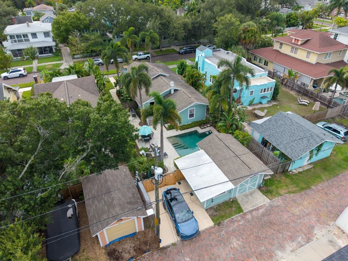 Aerial view of a turquoise home, swimming pool and palm trees