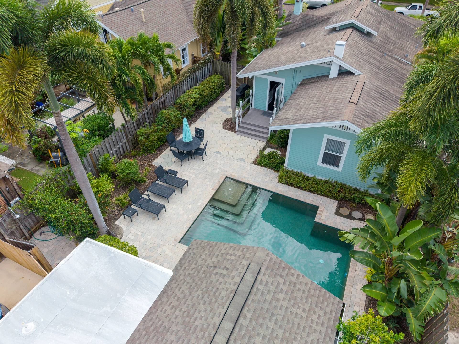 Turquoise home and pool terrace framed by tropical landscaping