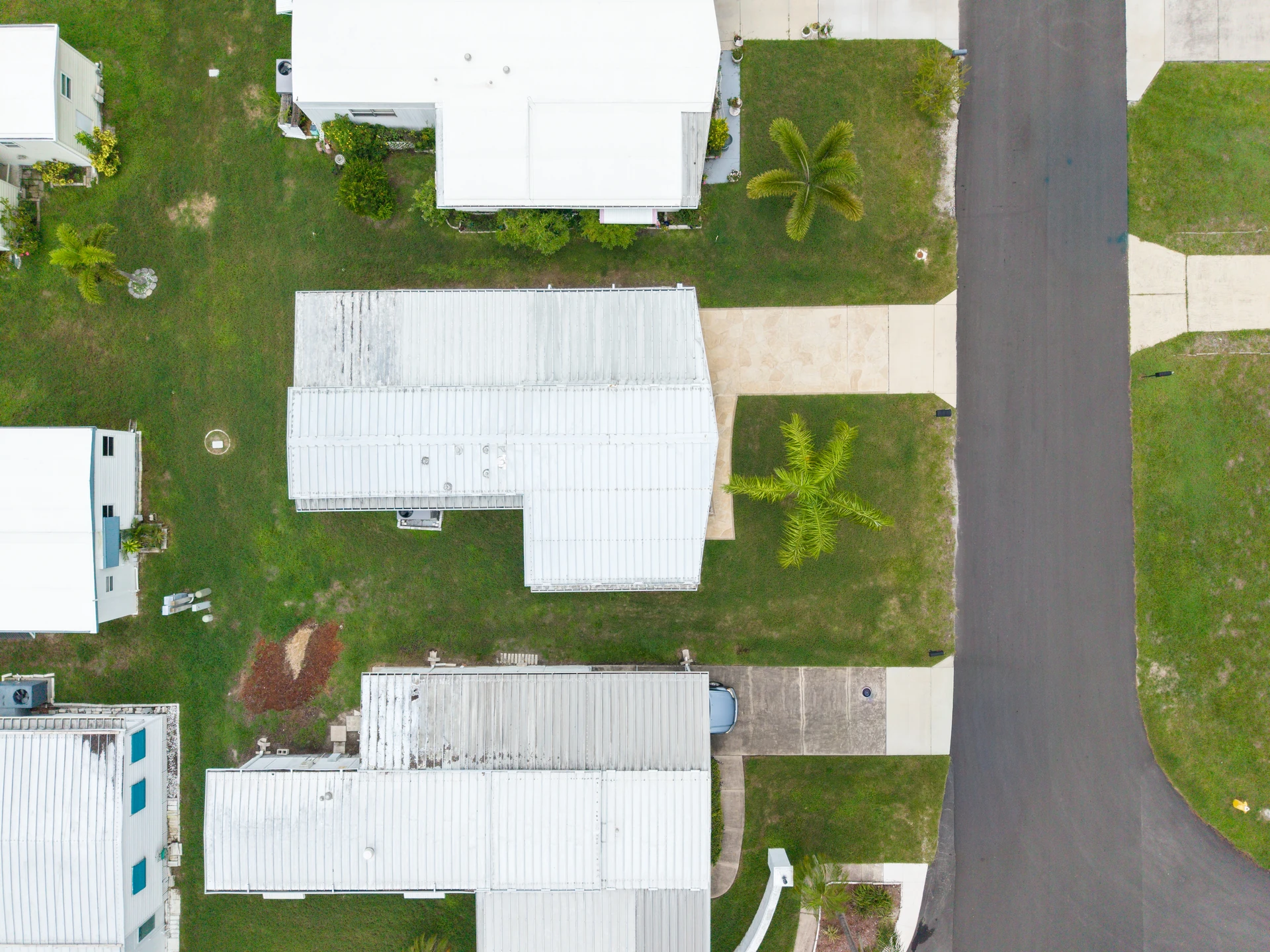 Overhead view of homes, lawns and a straight residential road
