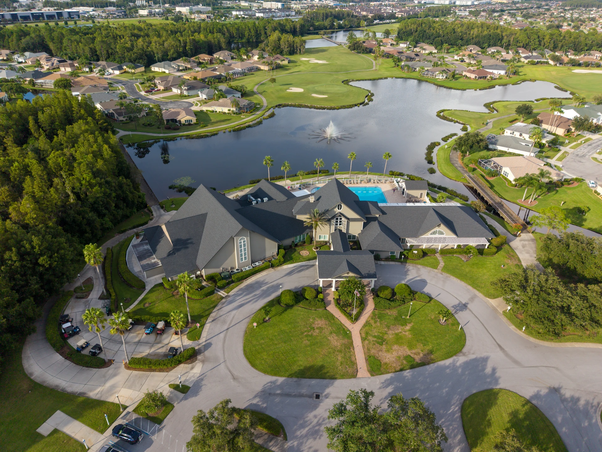 Clubhouse and landscaped circular drive beside a lake
