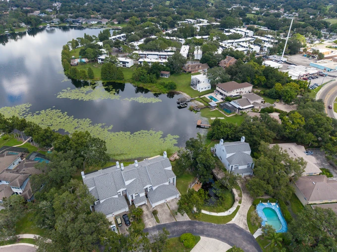 Lakeside home with a curved driveway and a backyard pool, viewed from above