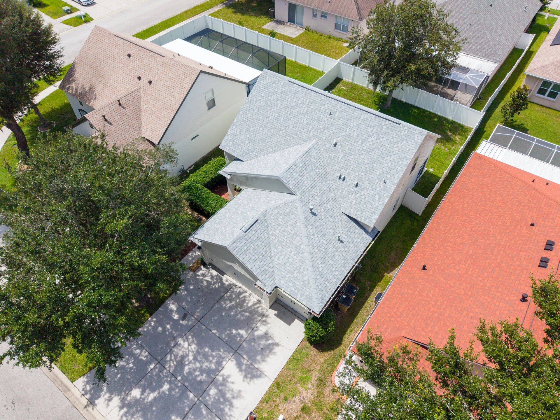 Aerial view of a gray-roofed home with a screened patio
