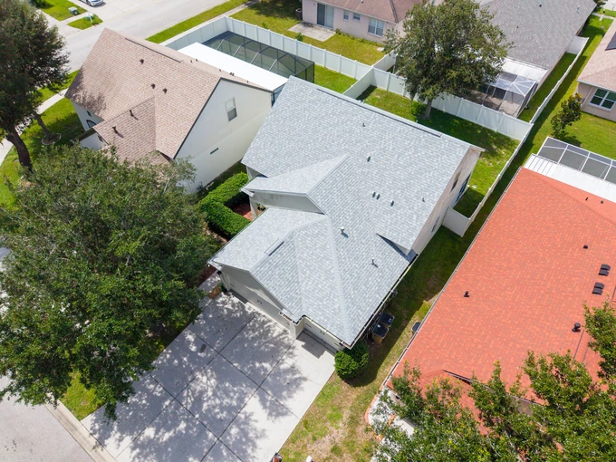 Aerial view of a gray-roofed home with a screened patio