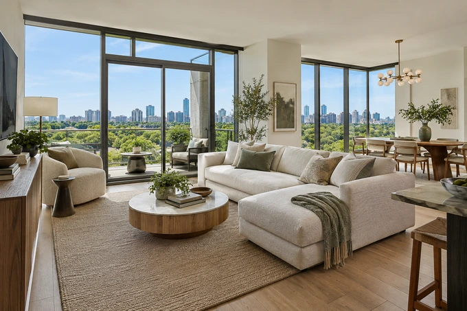Light-filled condominium living room with city-and-treetop outlook, pale sofa and coherent adjoining dining space