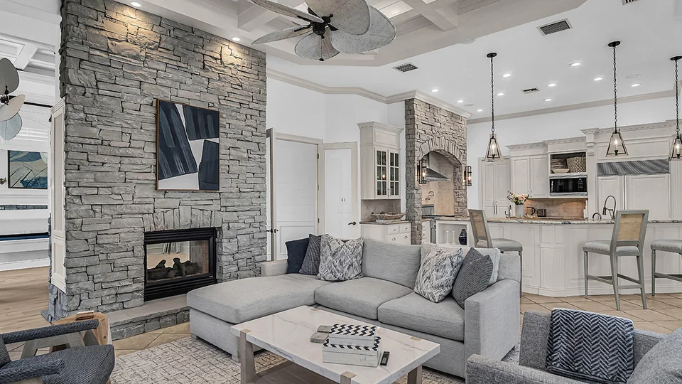 Living room with a stone fireplace, sectional sofa and open kitchen